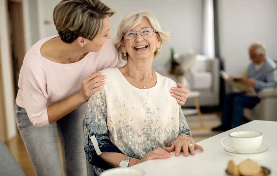 Eine Seniorin und ihre Begleiterin lachen gemeinsam