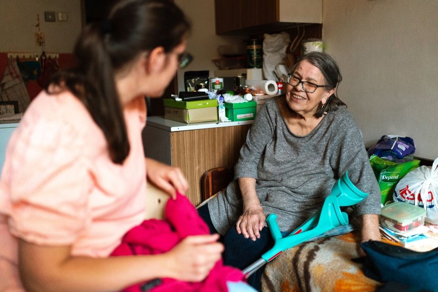 Eine Seniorin und ihre Betreuungsperson im Gespräch zu Hause