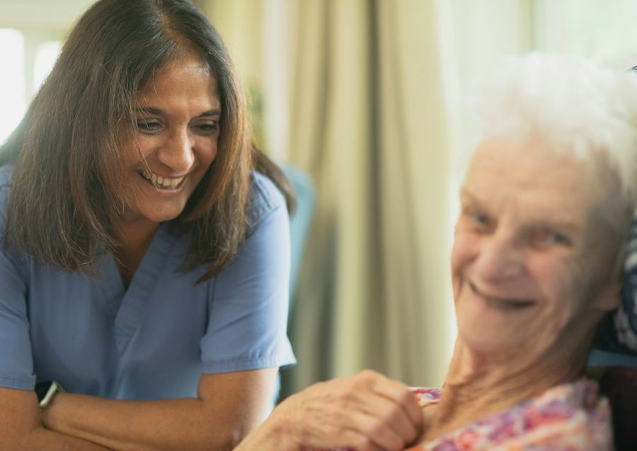 Eine Betreuungsperson und eine Seniorin lachen gemeinsam