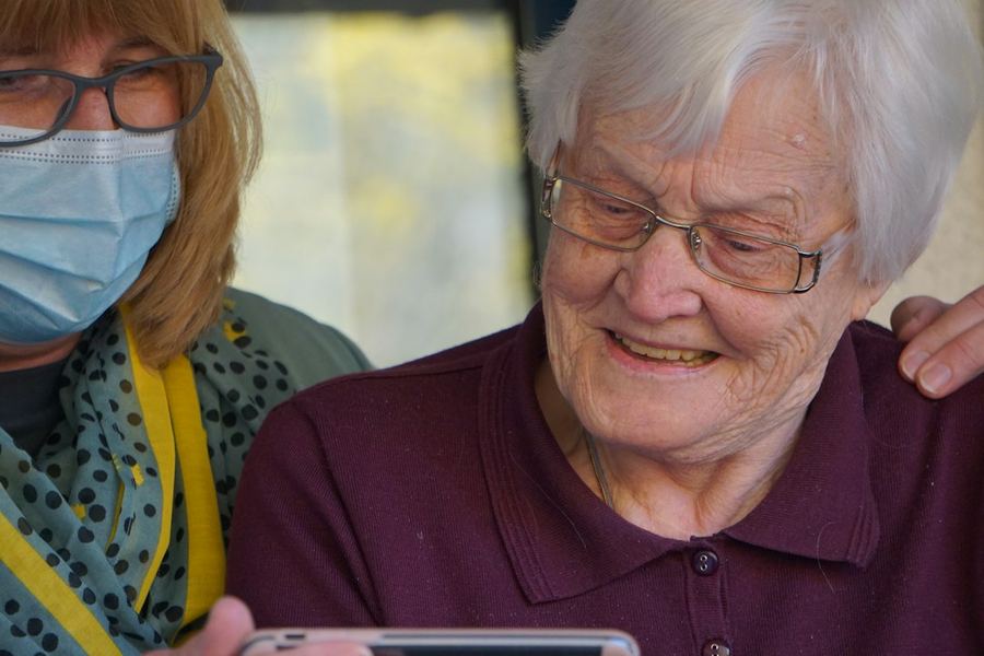Eine Seniorin erhält Unterstützung beim Betrachten eines Bildschirms